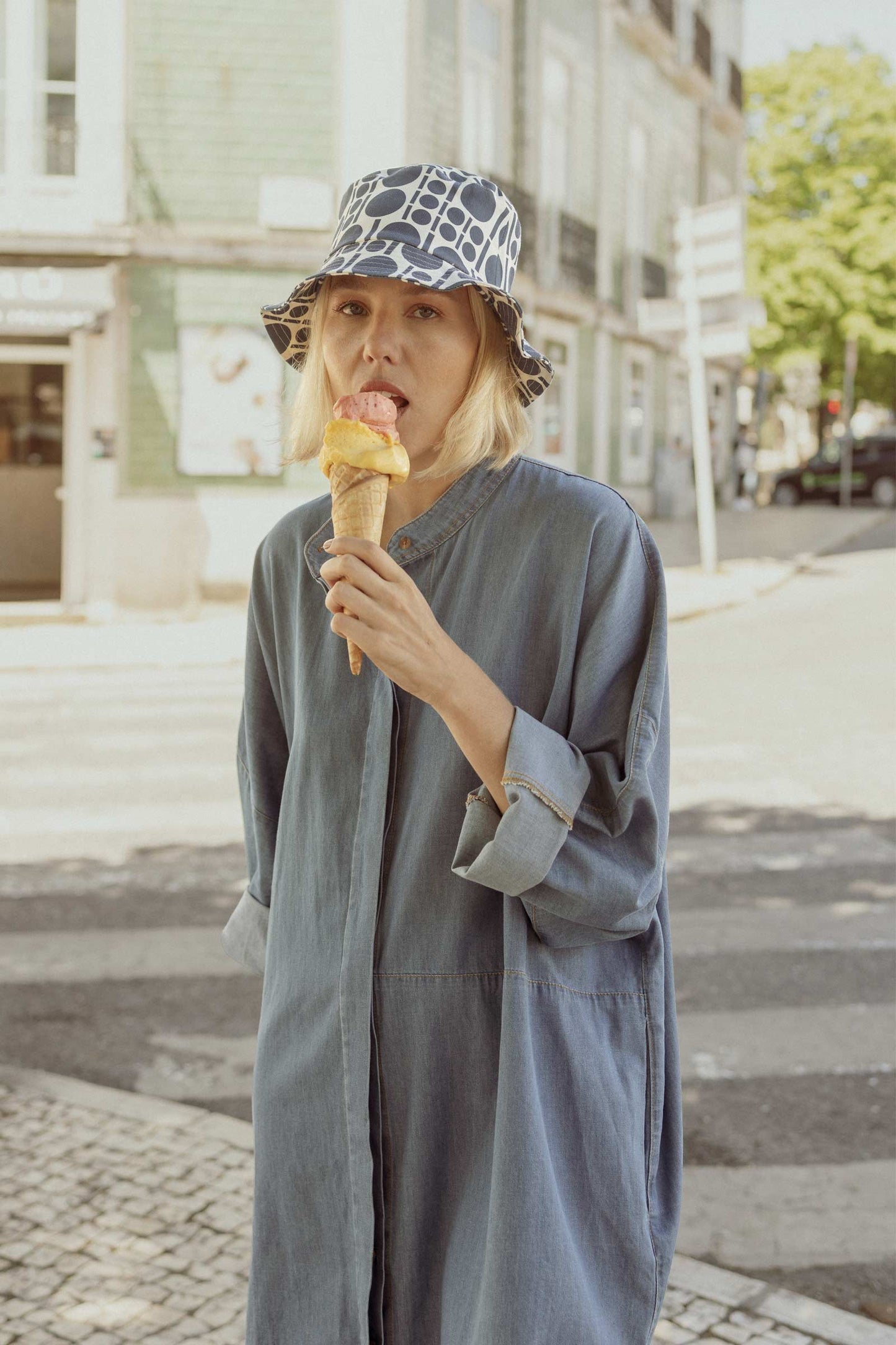 Model having ice cream and wearing a 10 to 10 denim shirt dress and hat