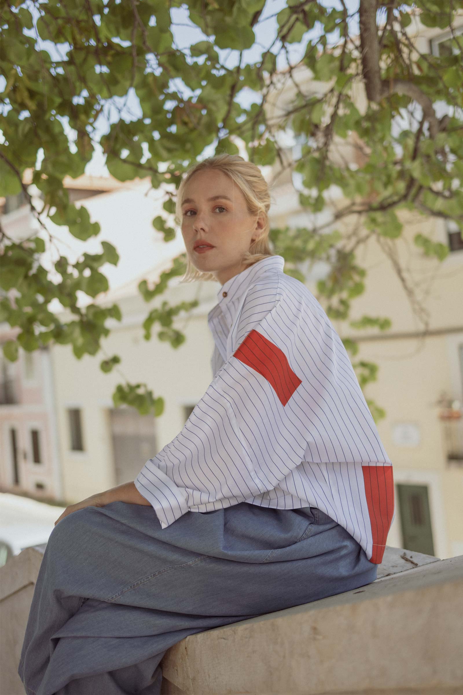 Model wearing 10 to 10 oversized striped white and blue shirt with coral rectangles pattern in the back